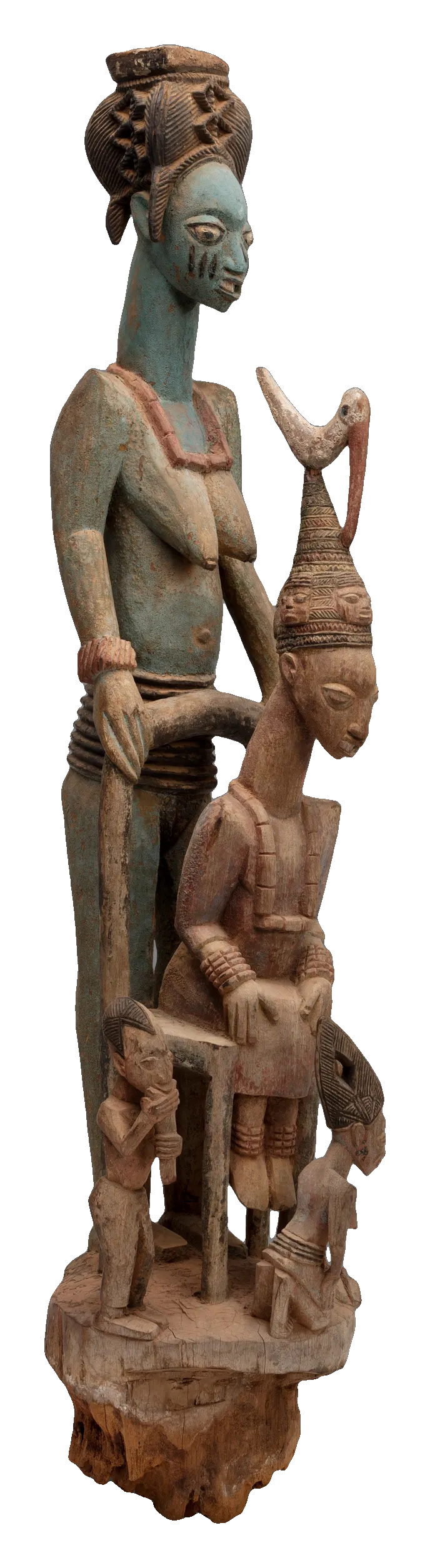 A tall carved wooden post: a seated king wearing a high crown, with a standing woman behind him and smaller figures below.